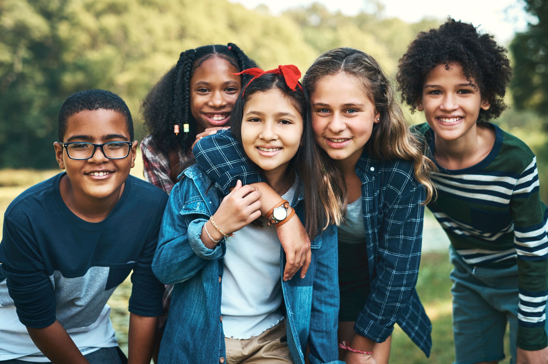 Shot of a group of teenagers embracing in nature at summer camp